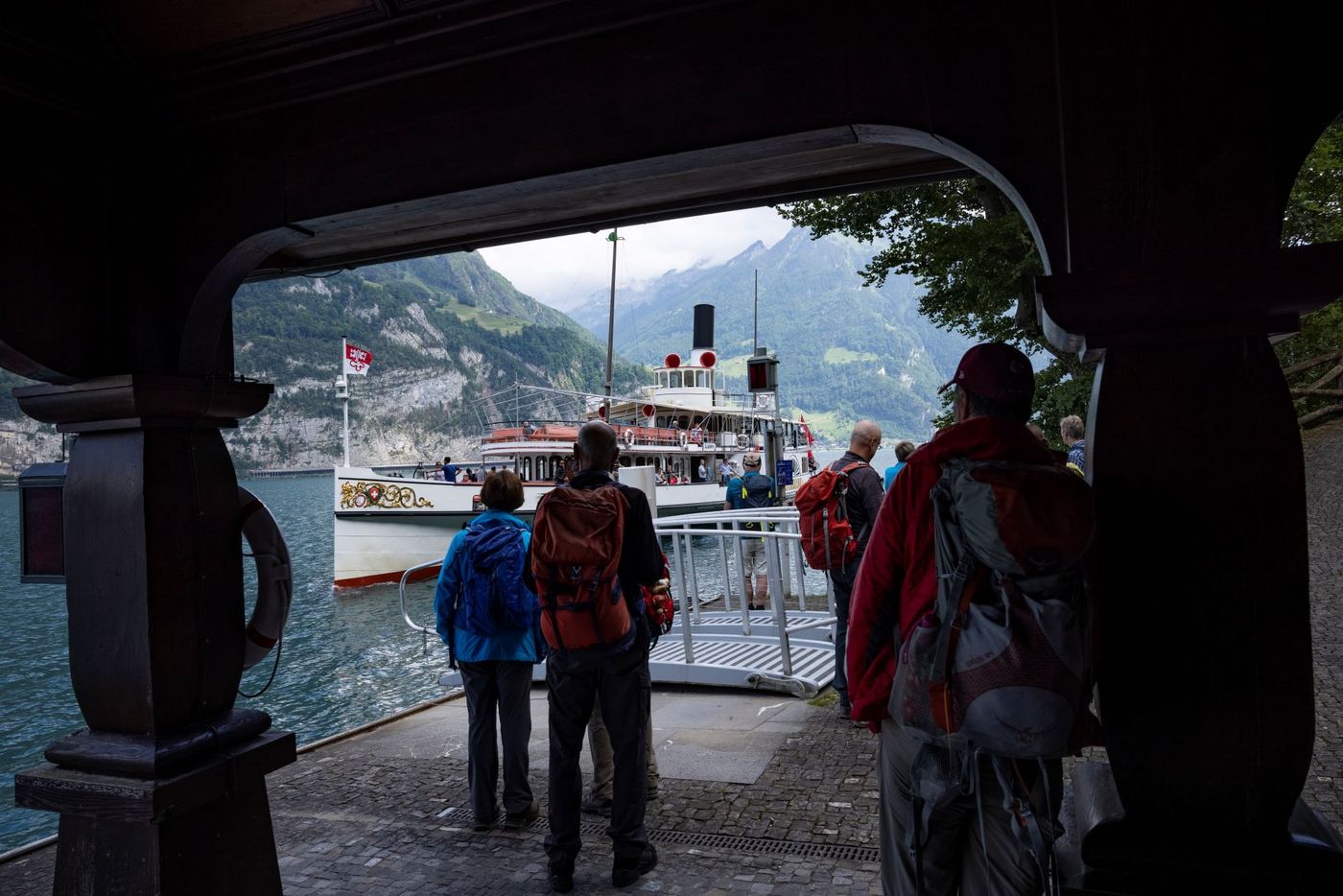 Hikers waiting on a covered stone pier near the dock on Lake Lucerne, Switzerland-supplied by Eurortrek