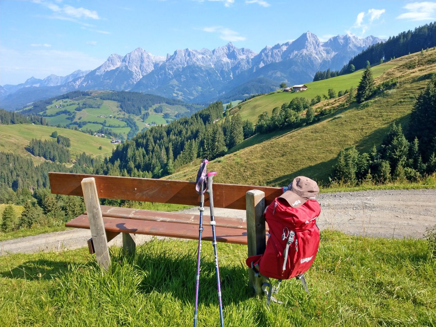 Red backpack hanging at a bench in the quintessential spirit of an Alpine summer hike in Austria - supplied by Eurohike